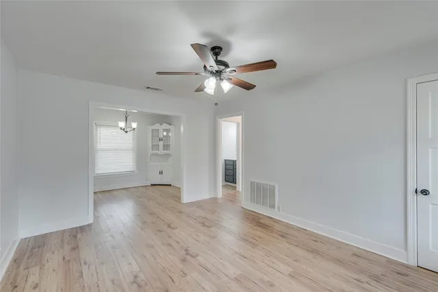 a view of a room with wooden floor a ceiling fan and windows