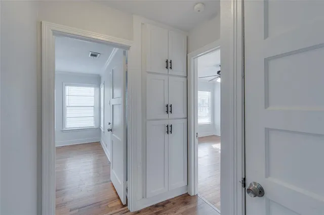a view of empty room with wooden floor and fan