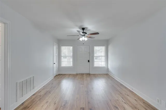 a view of a room with wooden floor and a ceiling fan