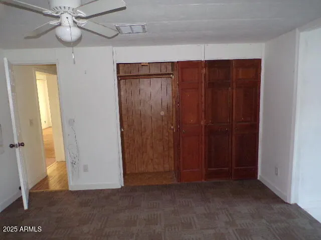 an empty room with windows closet and fan