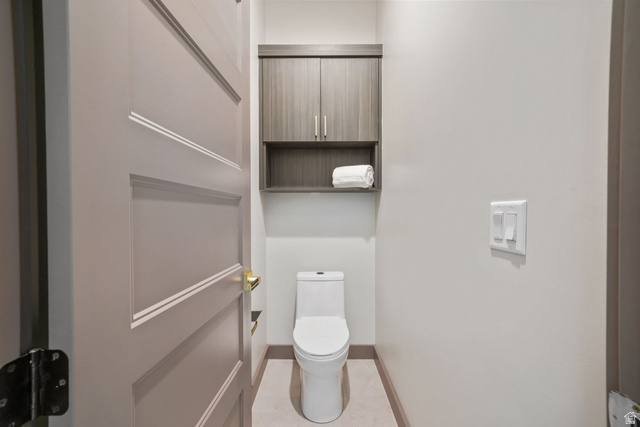 10646 North Reflection Ridge Hideout, UT 84036 - Photo 35 of 43 Compact lavatory featuring a white toilet, contemporary wall-mounted cabinetry with an open shelf, light wall paint, and coordinating floor tiles