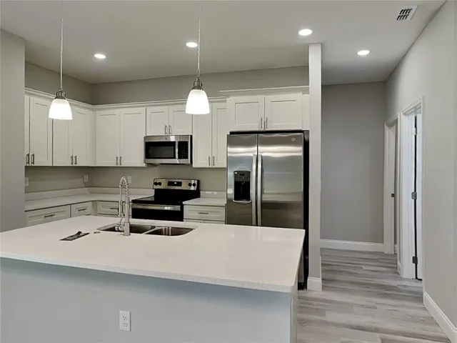 a kitchen with stainless steel appliances a refrigerator a stove a microwave and white cabinets