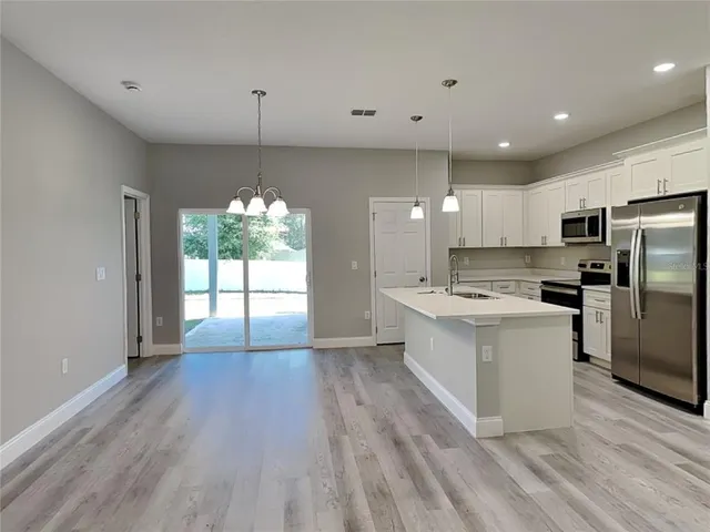 a large kitchen with granite countertop a large counter top a sink stainless steel appliances and cabinets