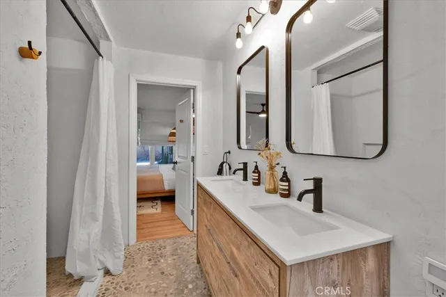 a bedroom with a bed cupboard mirror and window