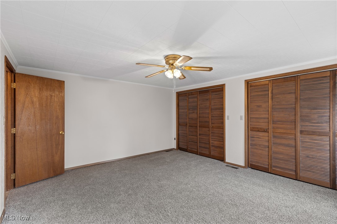 59638 Broadview Road Shadyside, OH 43947 - Photo 18 of 43 Unfurnished bedroom with crown molding, a ceiling fan, multiple closets, and carpet floors