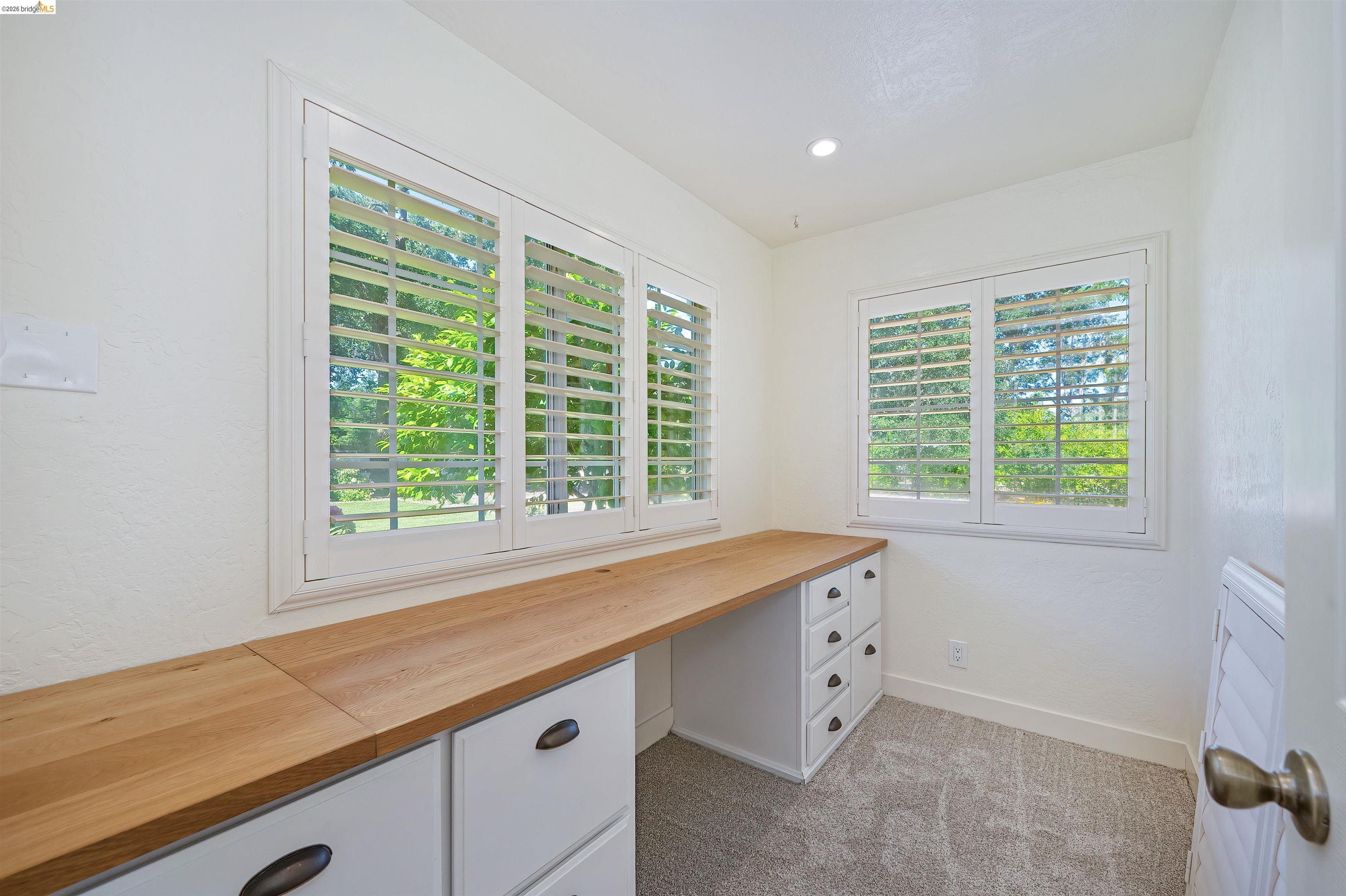 10474 Sheldon Road Elk Grove, CA 95624 - Photo 27 of 83 Dedicated room featuring an integrated wood-finish desk with white cabinetry, multiple windows with plantation shutters, recessed lighting, and carpet flooring