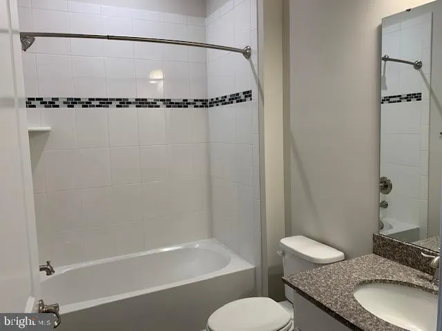 a bathroom with a granite countertop bathtub shower sink vanity and toilet