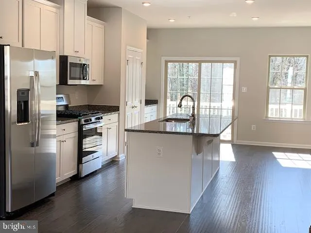 a kitchen with granite countertop a refrigerator stove top oven and sink