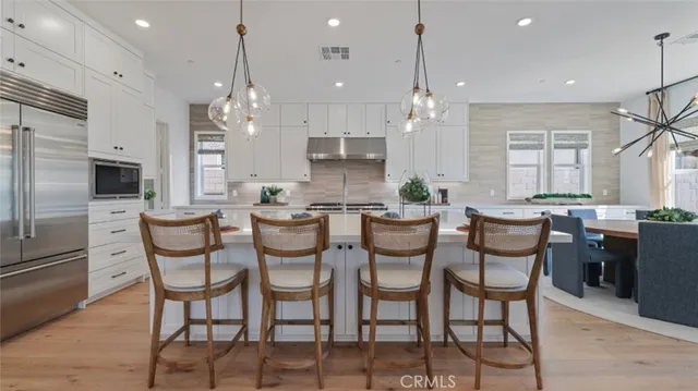 a kitchen with stainless steel appliances kitchen island granite countertop a stove a sink a dining table and chairs