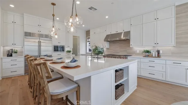 a kitchen with kitchen island granite countertop a sink a stove refrigerator and white cabinets with wooden floor