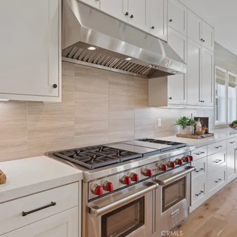 a kitchen with granite countertop a stove and a white cabinets