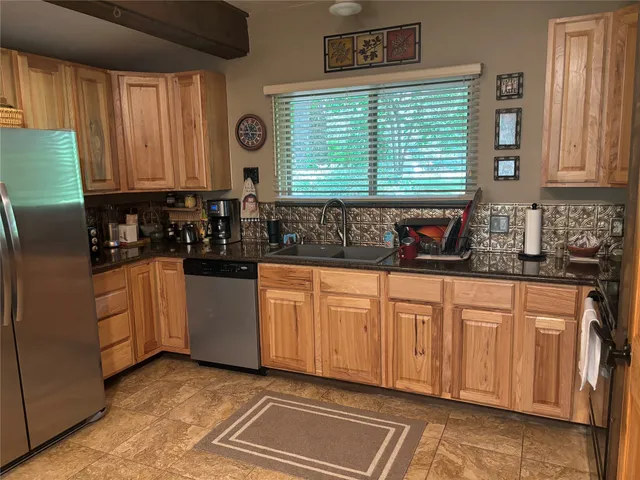 a kitchen with stainless steel appliances granite countertop white cabinets sink and a large window