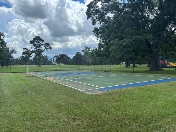 a view of a tennis ground with large trees