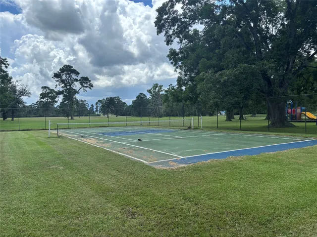 a view of a tennis ground with large trees