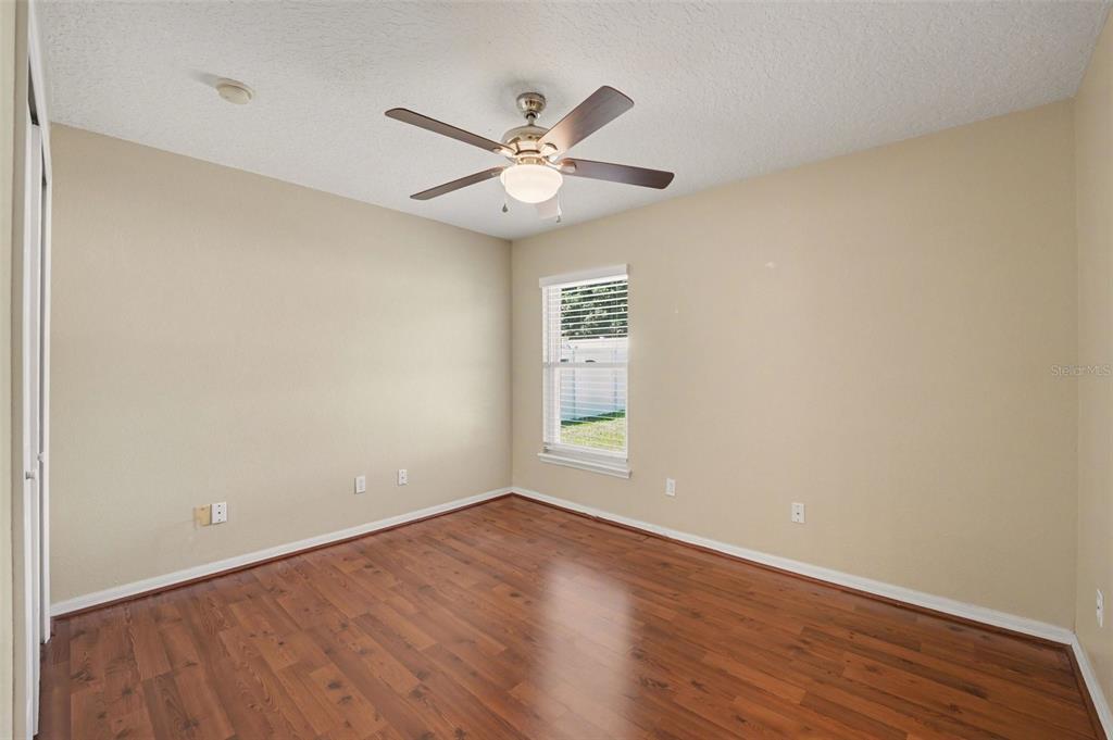 122 Costa Loop Auburndale, FL 33823 - Photo 21 of 30 a view of an empty room with wooden floor and a ceiling fan