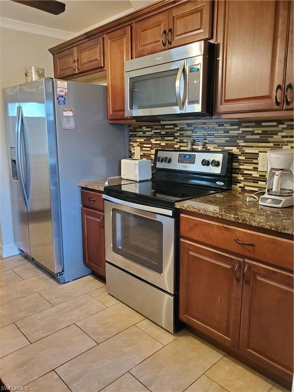 a kitchen with granite countertop a stove top oven cabinetry and refrigerator