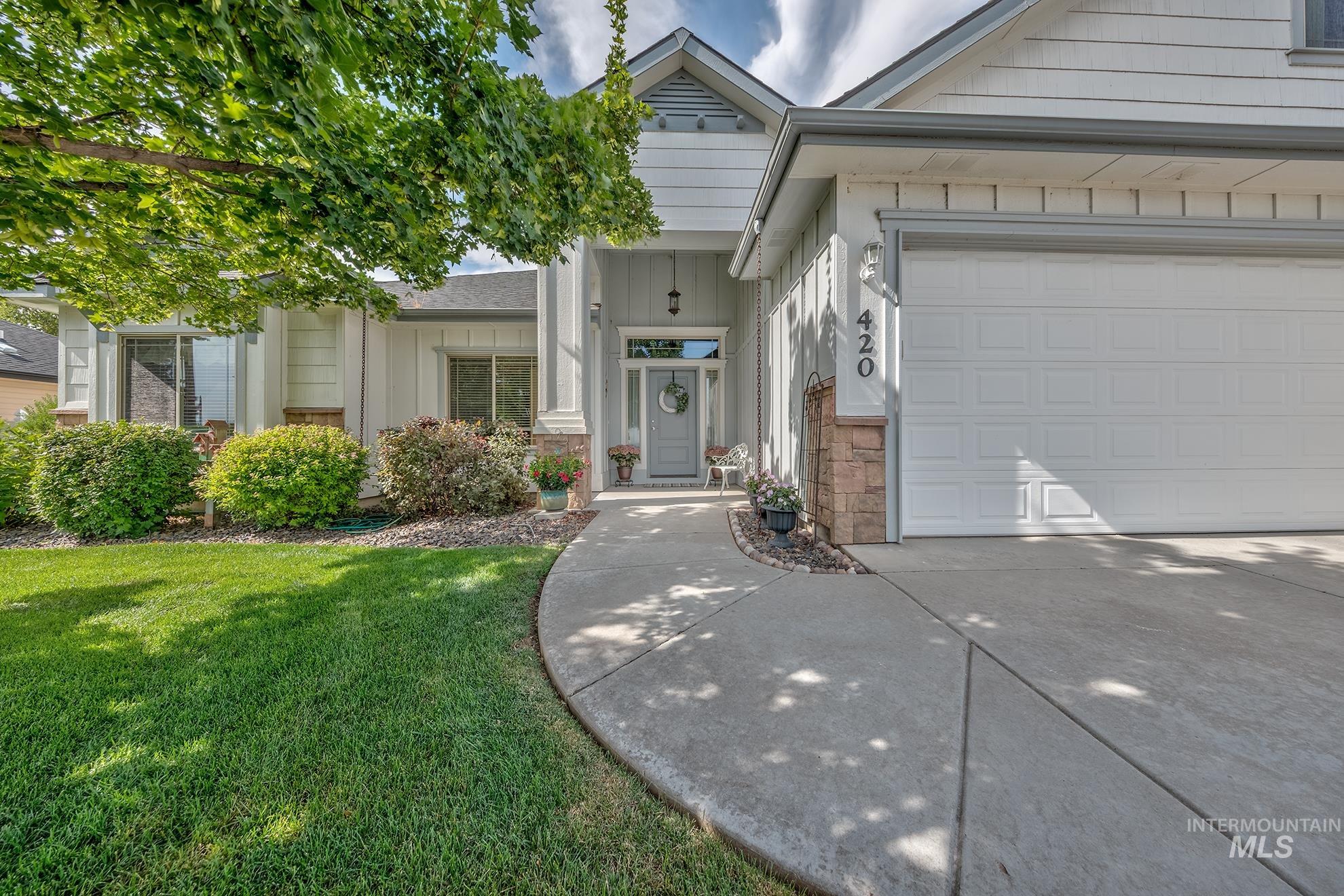 Inviting front exterior featuring a covered entry, white siding, stone accents, a two-car garage, and a concrete pathway