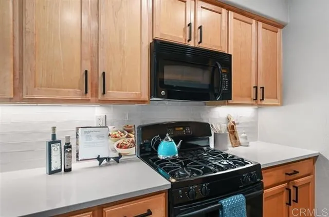 a kitchen with granite countertop a stove a microwave a sink and cabinets
