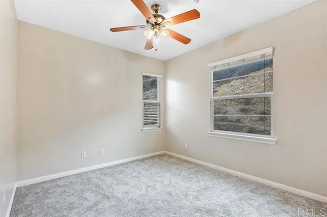 an empty room with a window and a fan