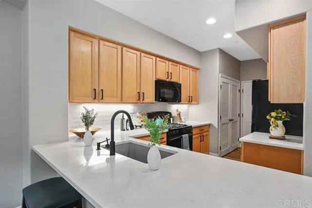 a kitchen with stainless steel appliances a sink a microwave a stove and white cabinets