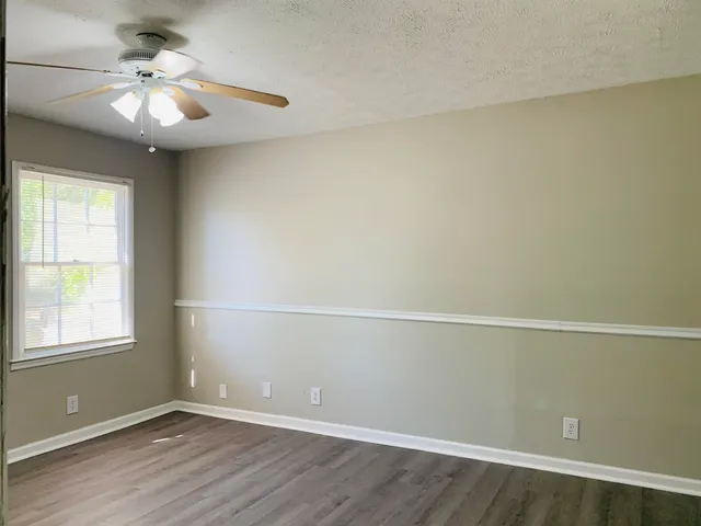 an empty room with a window and a ceiling fan