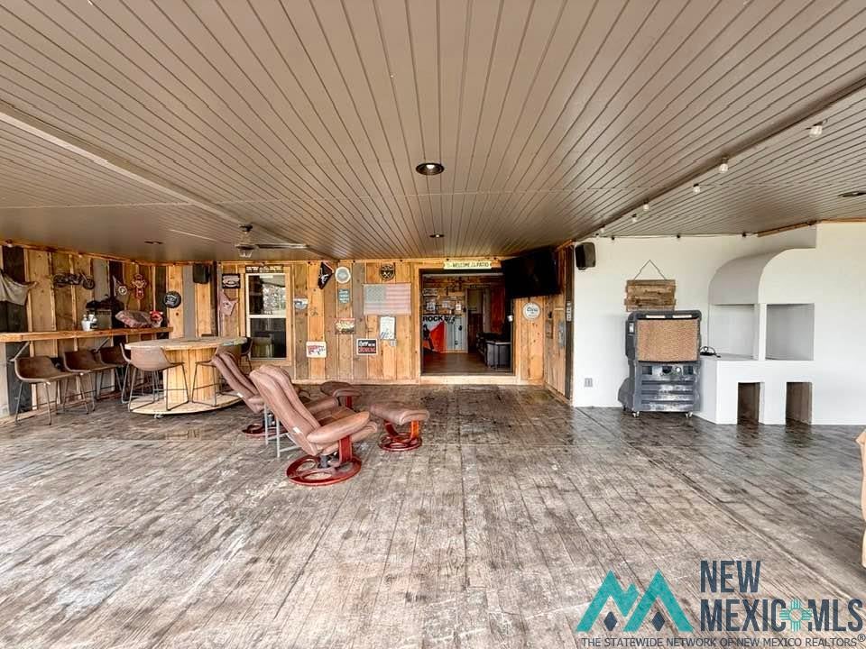 5404 Sioux Road Carlsbad, NM 88220 - Photo 63 of 100 Spacious covered outdoor area featuring wood-finish flooring, a built-in bar with seating, exposed wood-paneled walls, a slatted ceiling, and an integrated outdoor fireplace structure