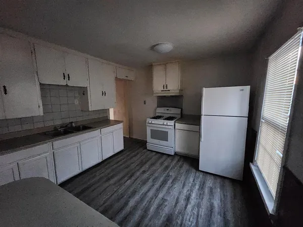 a kitchen with sink a refrigerator and white cabinets