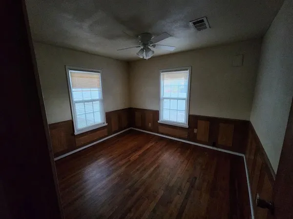 an empty room with wooden floor and windows