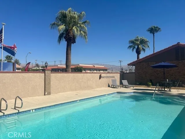 a view of a swimming pool with a lawn chairs under an umbrella