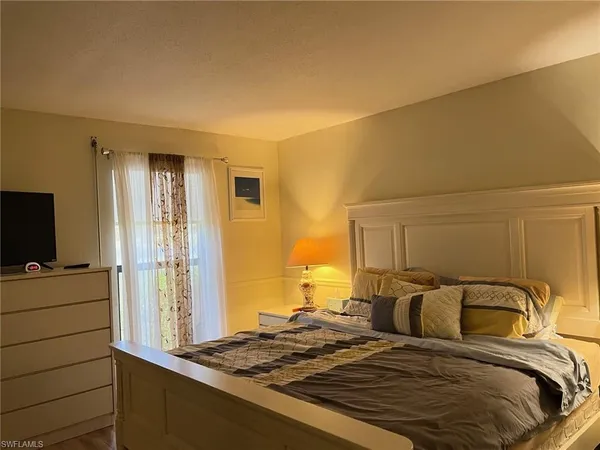 a bedroom with a bed and a flat tv screen on a dresser