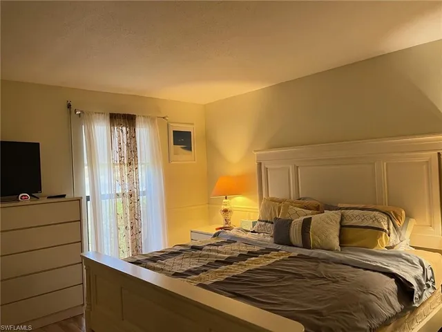 a bedroom with a bed and a flat tv screen on a dresser