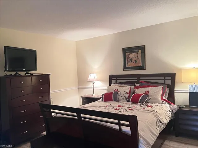 a bedroom with a bed and a flat tv screen on a dresser