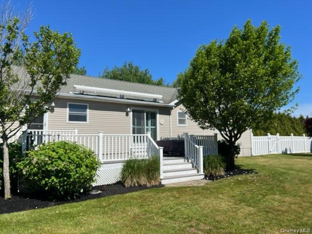 312 Riley Avenue Calverton, NY 11933 - Photo 22 of 30 Expansive backyard featuring a manicured lawn, a large deck with white railing, motorized awning, and mature trees