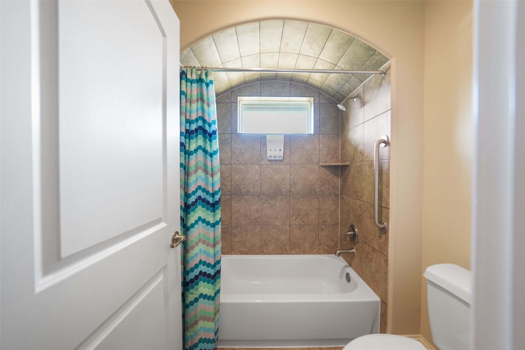 26250 B Riley Road Waller, TX 77484 - Photo 30 of 45 Guest bath offering a deep soaking tub with tile surround, arched ceiling detail, and a window providing natural light.