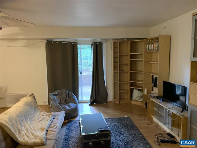 a living room with furniture a flat screen tv and a refrigerator