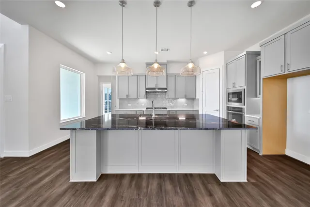 a large kitchen with stainless steel appliances granite countertop a large stove a sink dishwasher and a refrigerator with wooden floor