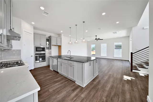 a kitchen with stainless steel appliances granite countertop a stove a sink and a refrigerator