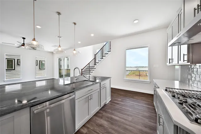 a kitchen with stainless steel appliances granite countertop a sink a stove and a wooden floors