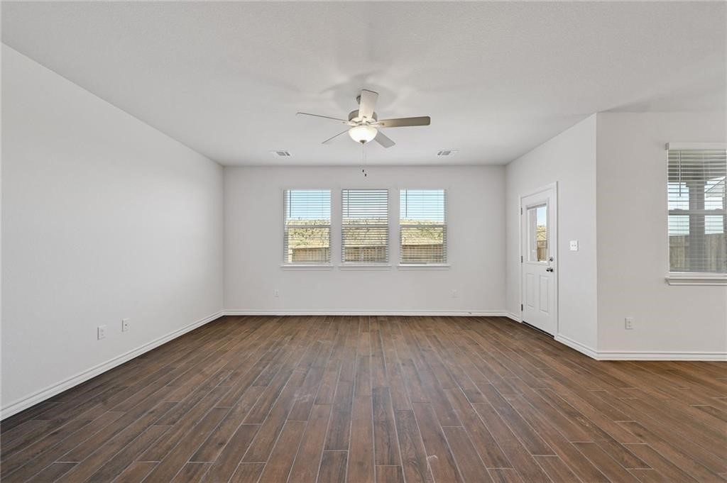 806 Pepperbark Loop Buda, TX 78610 - Photo 6 of 39 an empty room with wooden floor chandelier fan and windows