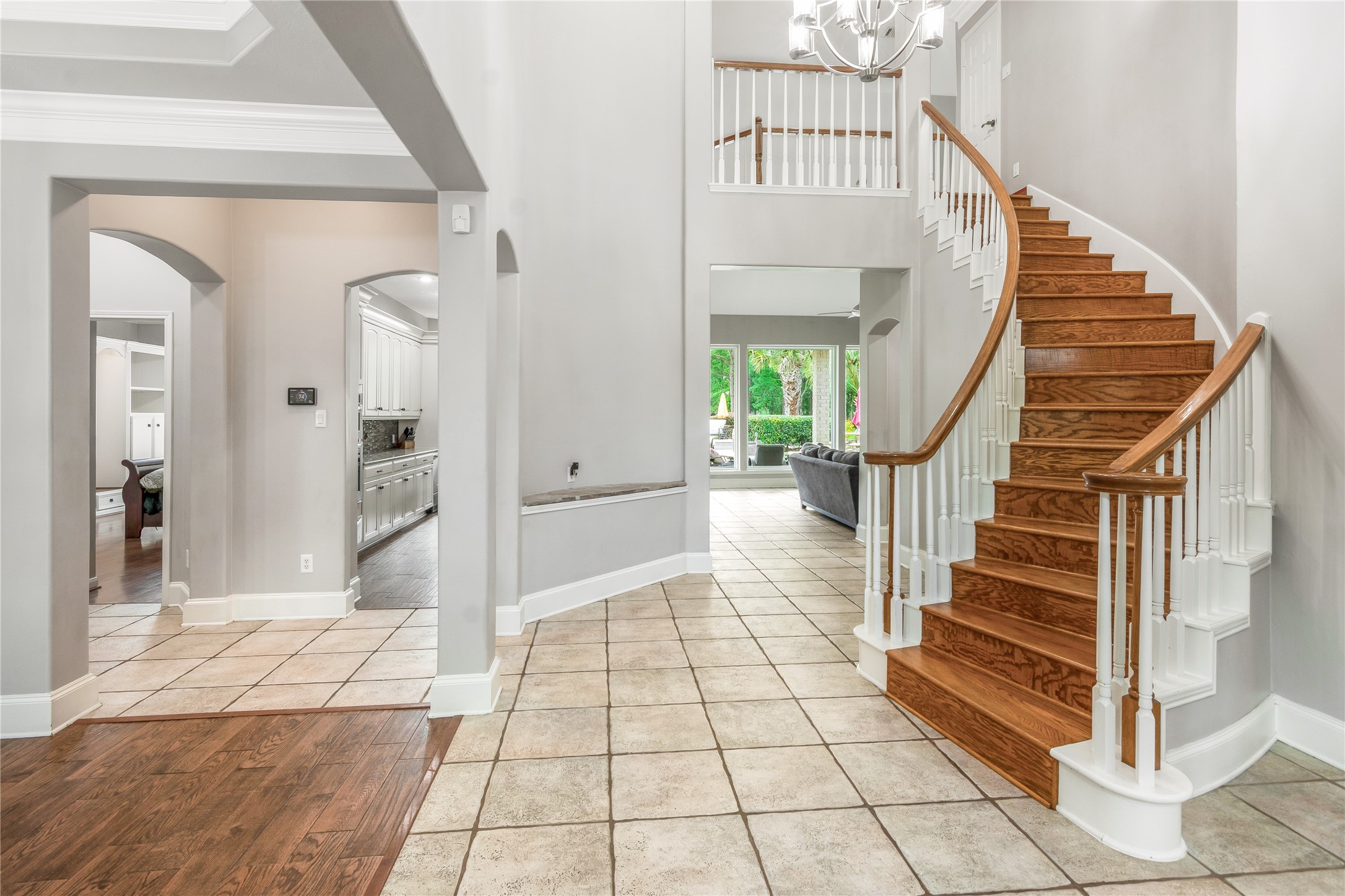 13914 Skinner Road Cypress, TX 77429 - Photo 6 of 50 Bright two story foyer with a curved hardwood staircase, high ceilings, arched openings, and an open view into the kitchen and living area.