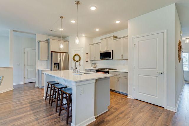 a kitchen with stainless steel appliances a sink a stove a refrigerator cabinets and wooden floor