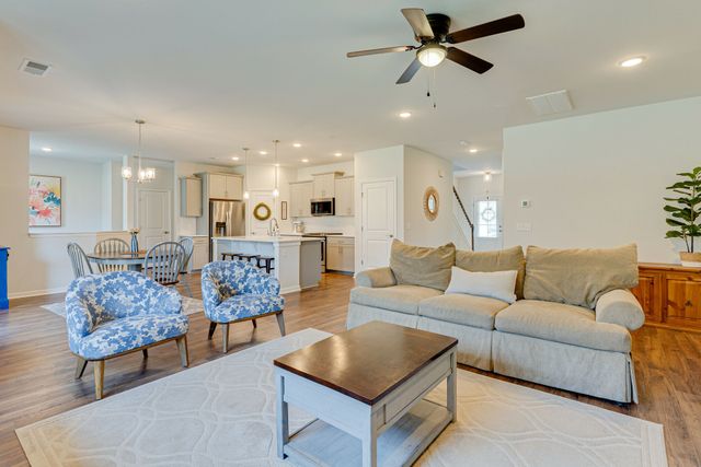 a living room with furniture kitchen view and a chandelier