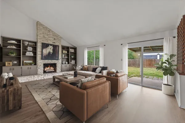 a living room with furniture large window and wooden floor