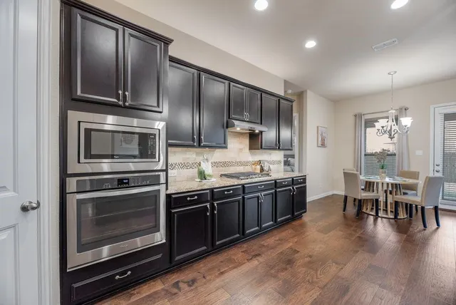 a kitchen with stainless steel appliances granite countertop a stove and chairs
