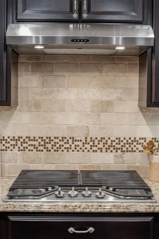 a large kitchen with stainless steel appliances kitchen island granite countertop a stove a sink dishwasher and a refrigerator with wooden floor