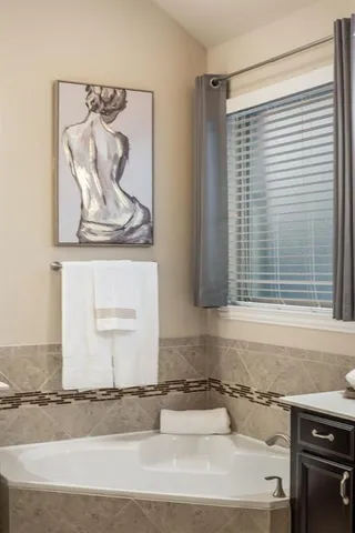 a spacious bathroom with a tub sink and a mirror