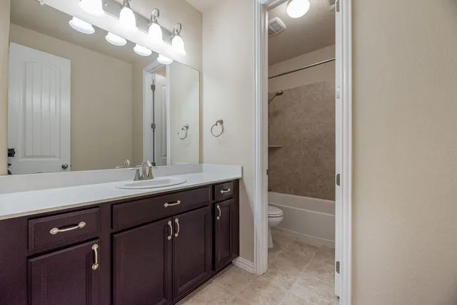 an empty room with a chandelier fan and windows