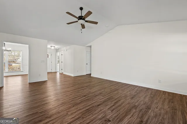 an empty room with wooden floor and ceiling fan
