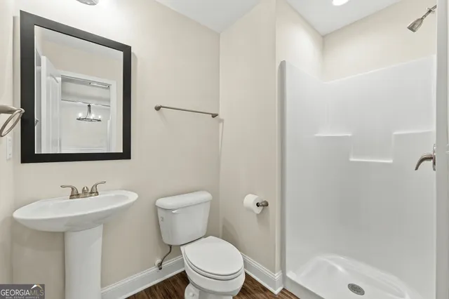 a bathroom with a toilet a sink a mirror and shower