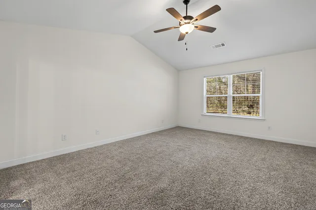 an empty room with windows and ceiling fan